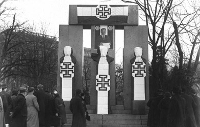 Das Denkmal der Republik mit Büsten von Victor Adler, Jakob Reumann und Ferdinand Hanusch wurde nach dem Februar 1934 mit Kruckenkreuz-Fahnen und einem Dollfuß-Bild überzogen. (© Bildarchiv Austria)